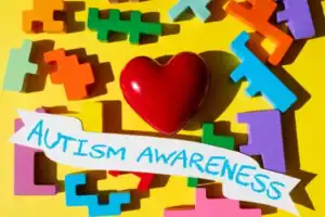 Colorful puzzle pieces with a red heart for autism awareness.