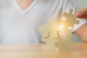Person assembling puzzle pieces symbolizing autism awareness and support.